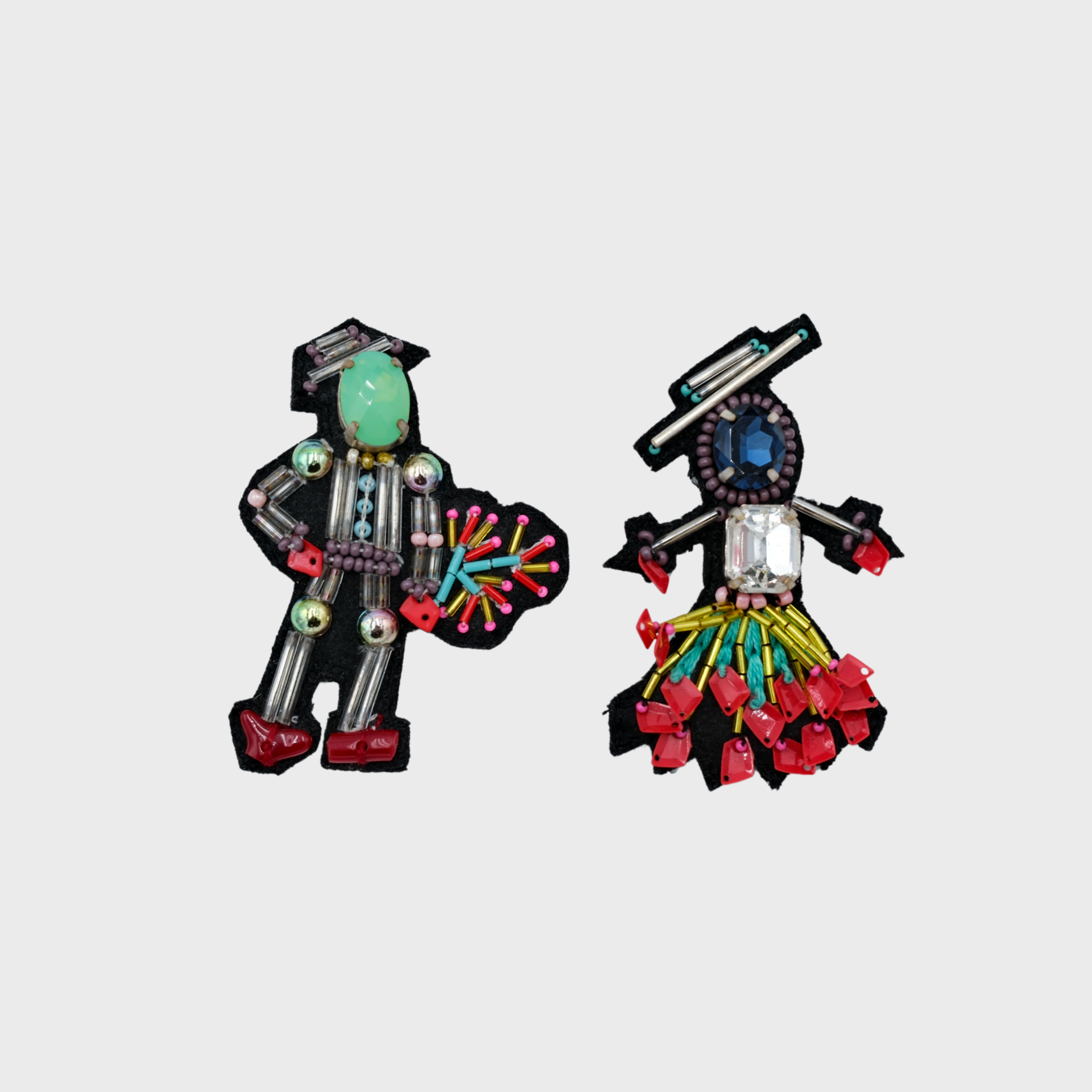 An embroidered set of two brooches representing a couple with grey, blue and red details. 
