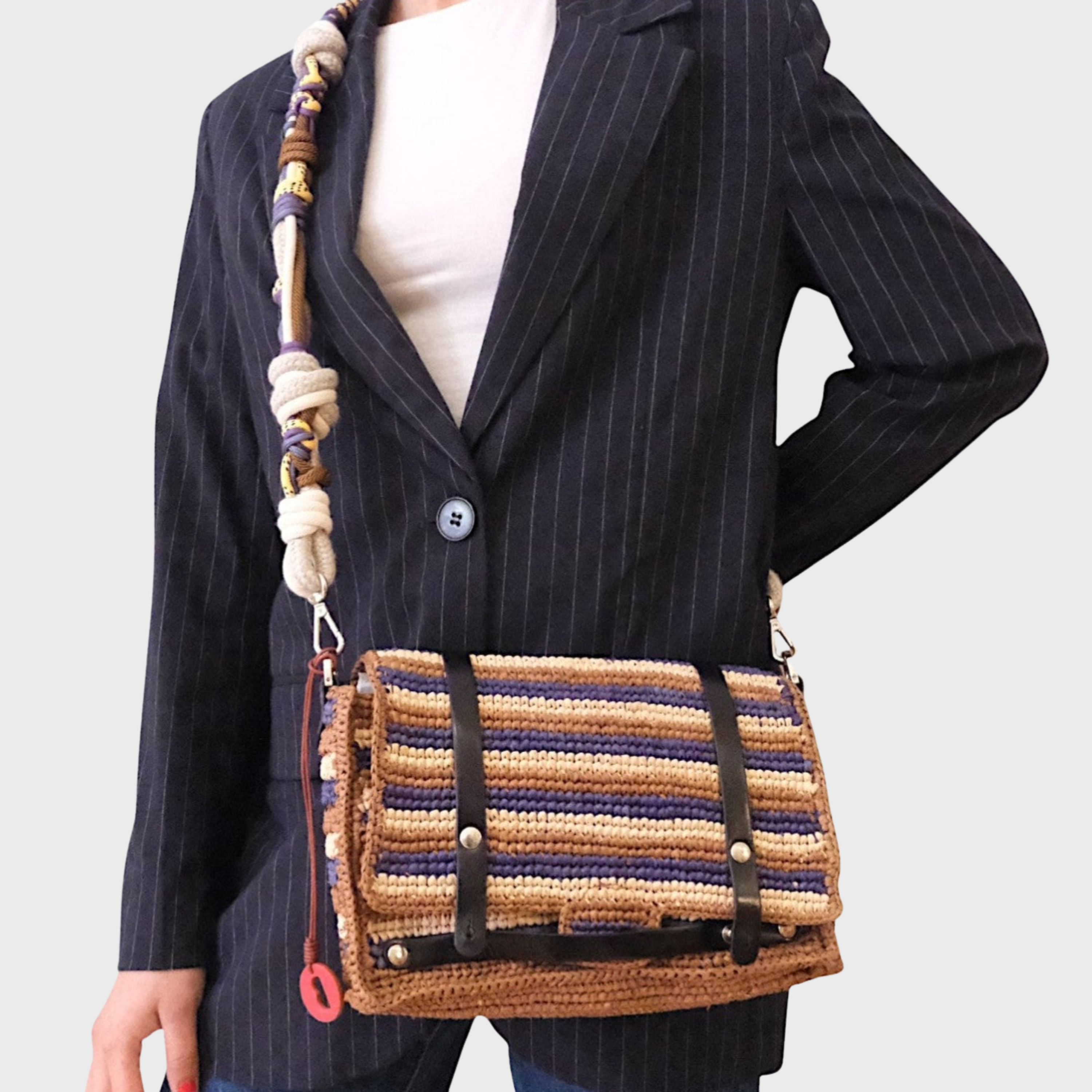 A modeal carrying the striped Bihan Shoulder bag with a bag strap. 