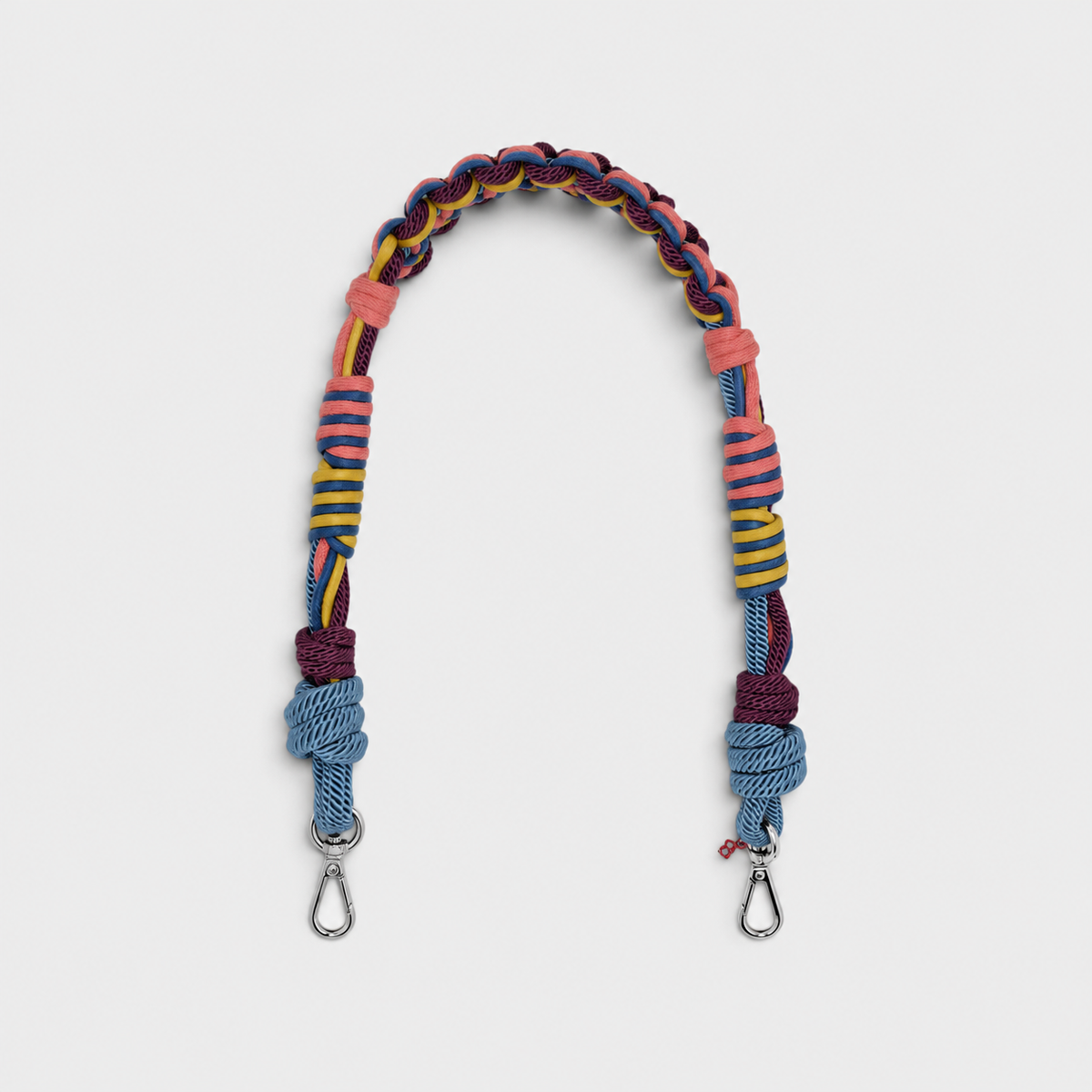 Multicolored braided macramé bag strap in coral, blue, yellow and purple with metal hooks on a light gray background.