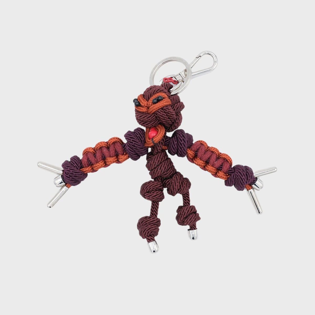 Macramé Keychain with a brown character on it representing a hawaian god. 