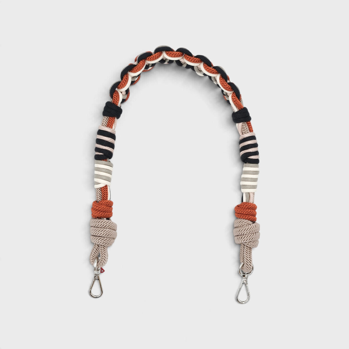Braided macramé bag strap with grey, white, black and red accents on a light gray background