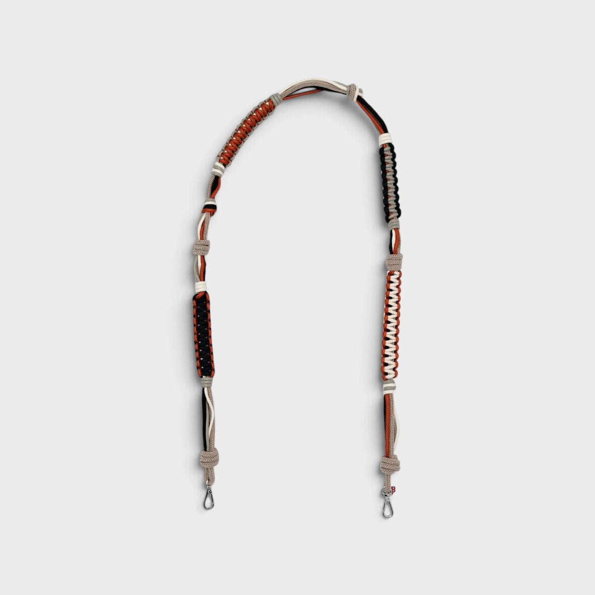 A macramé terracotta, black and grey bag strap. 
