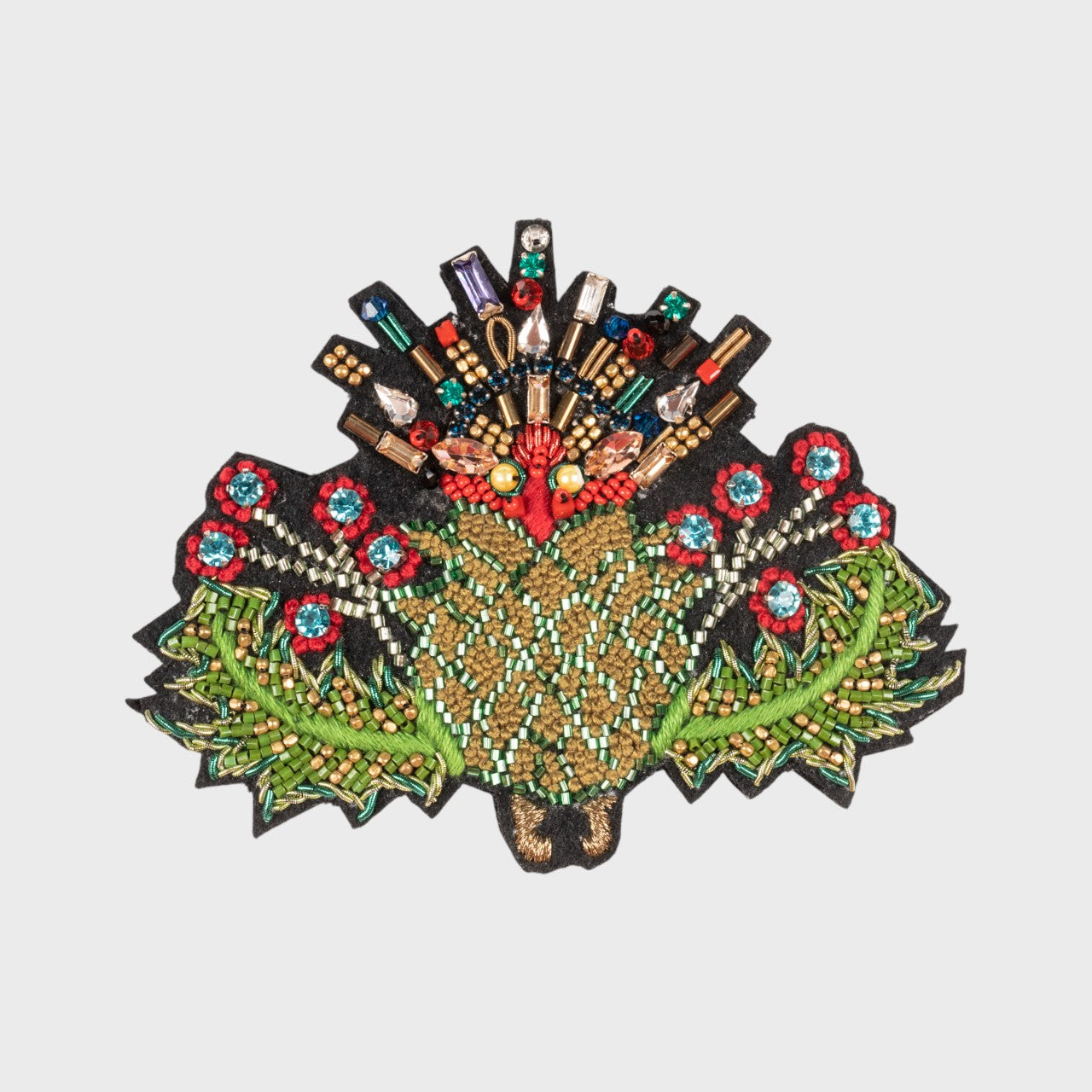 An embroidered brooch representing a thistle flower with red, green and blue details. 