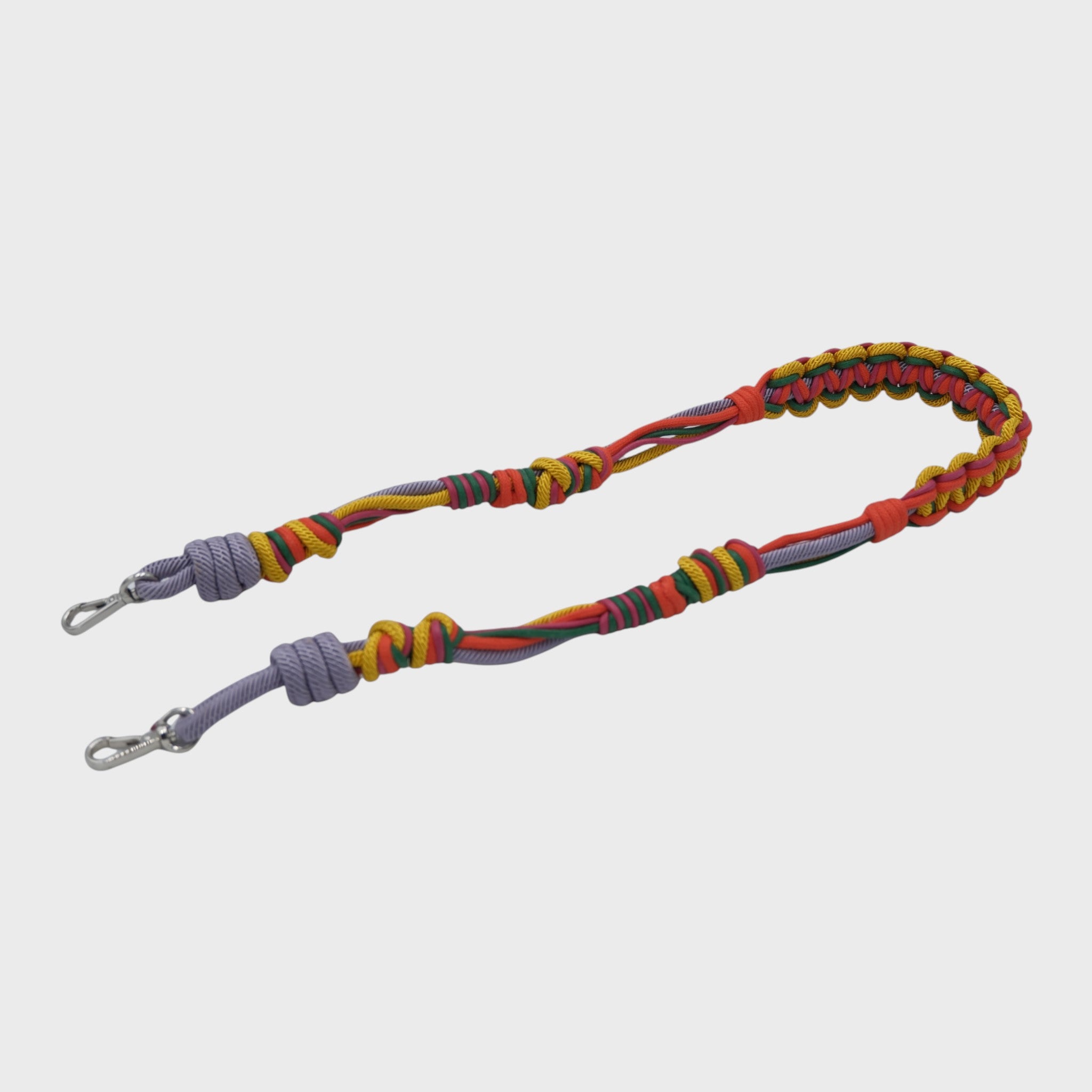 Multicolored braided macramé bag strap in yellow, lilac, orange, and green shown on a light gray background.