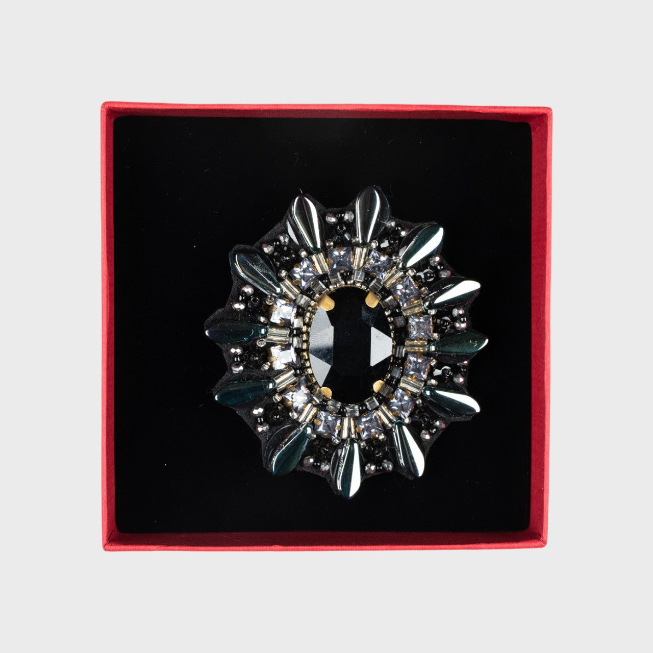 An embroidered brooch representing a black turtle back in a box. 