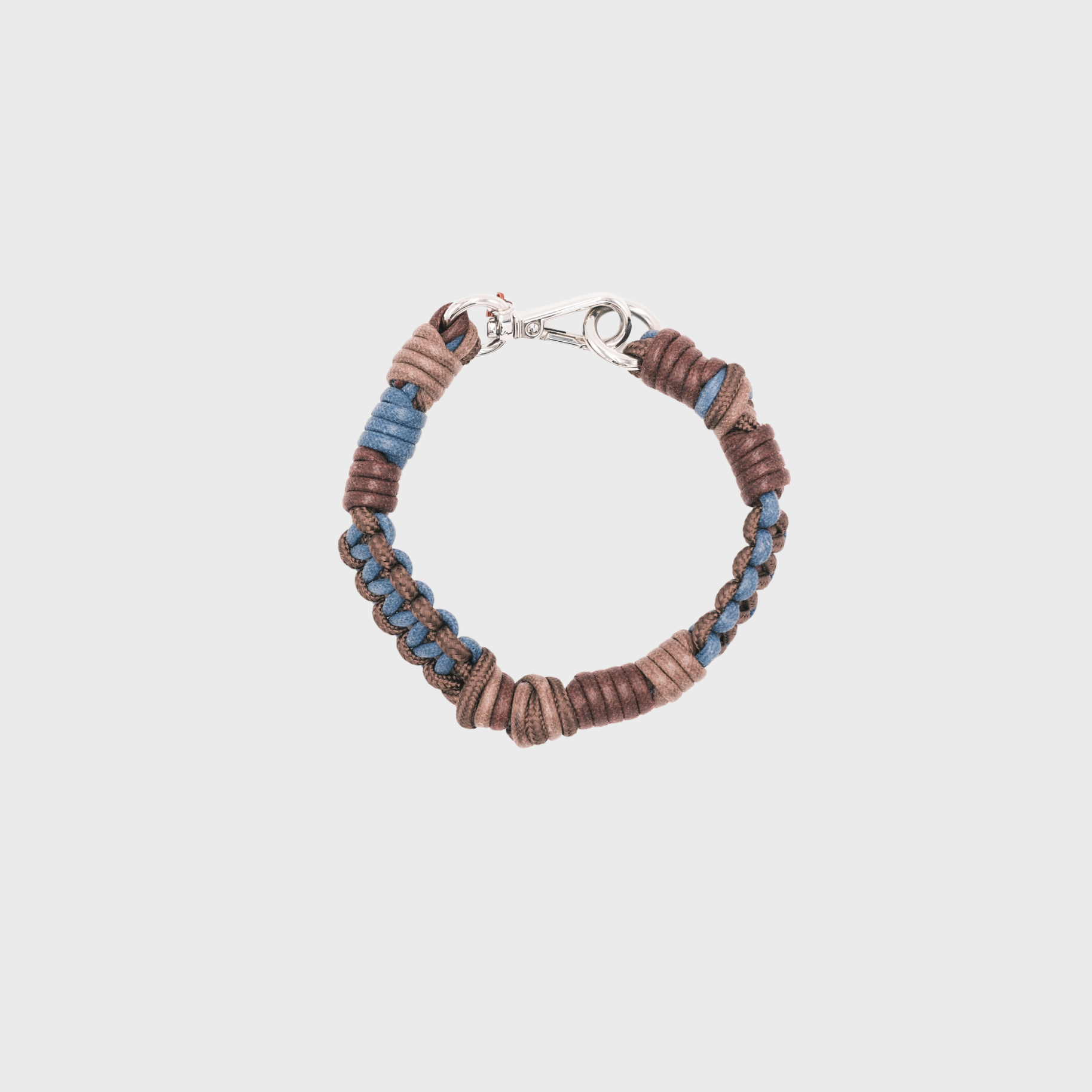 Photo taken from above of a braided macramé cord collar in shades of pink, peach, and beige with a silver clasp.