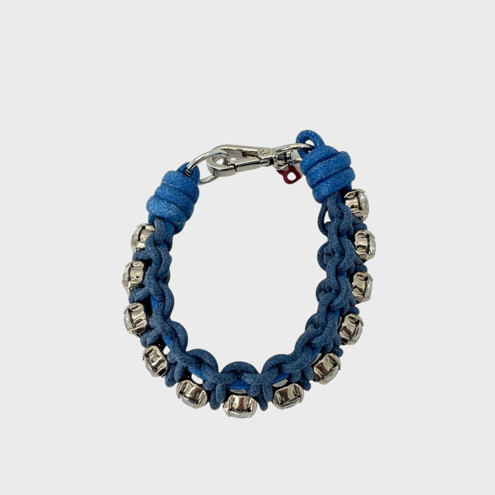 A handmade macramé woven bracelet featuring a mix of brown, and blue threads, accented with small white beads and a silver clasp.