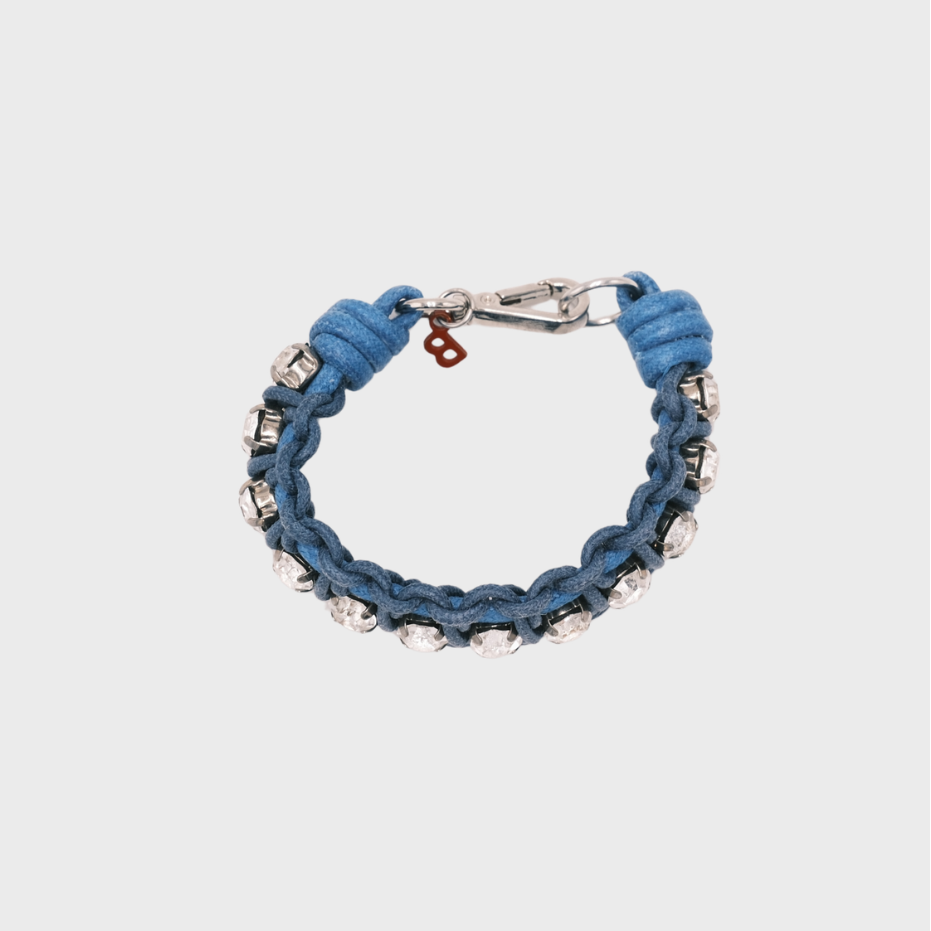 A handmade macramé woven bracelet featuring a mix of blue threads, accented with small white beads and a silver clasp.