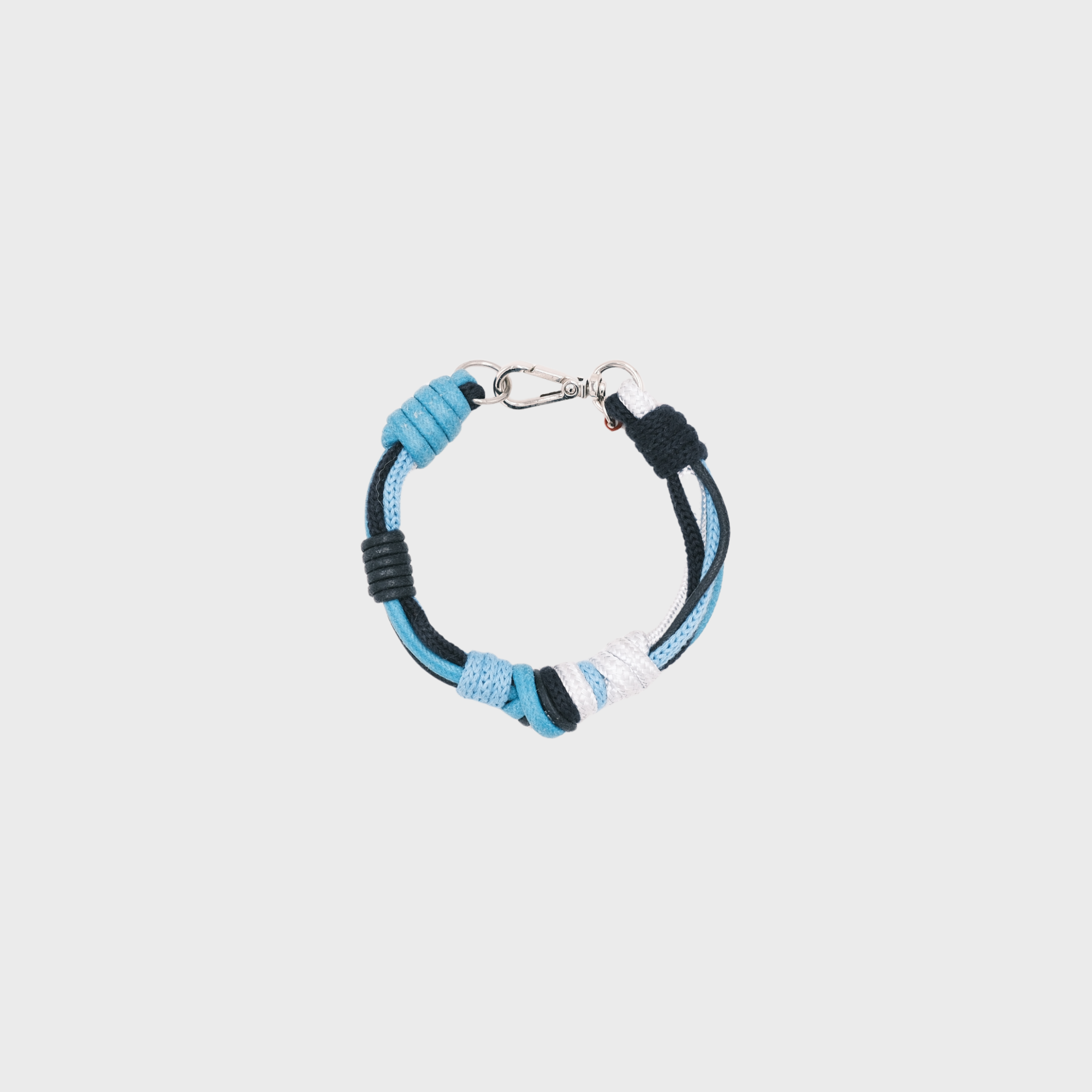 A photo taken from above of a knotted macramé bracelet in shades of blue and white, with a silver clasp.