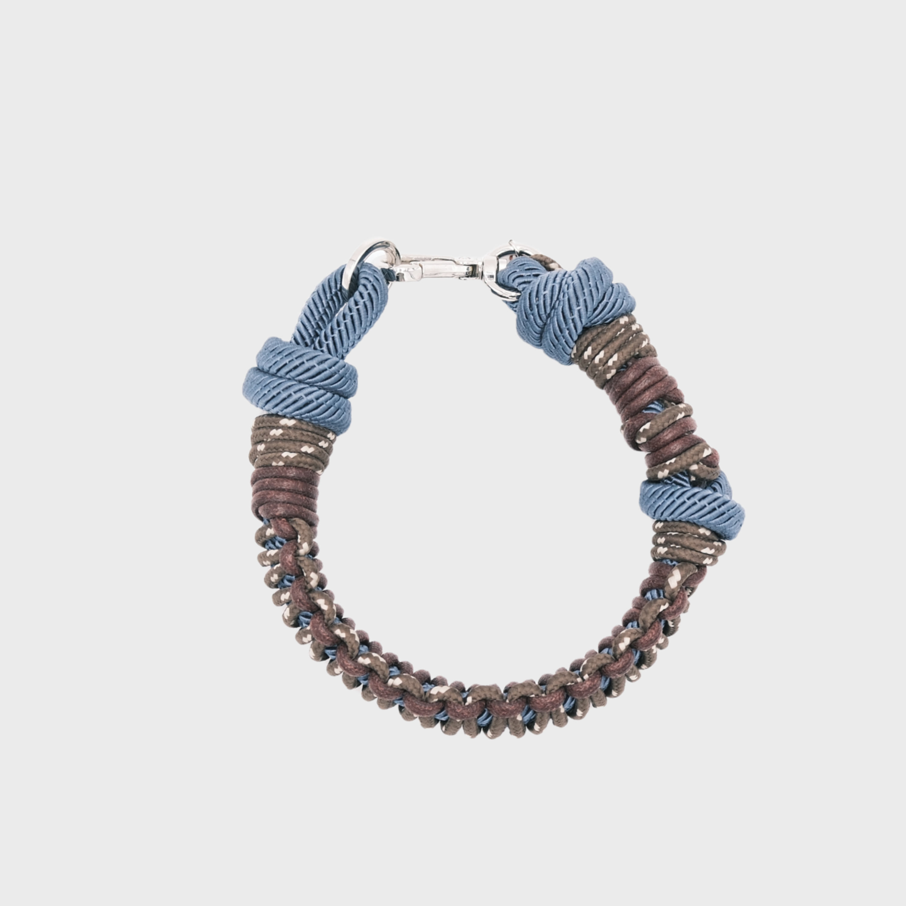 A photo taken from above of a braided macramé cord collar in shades of brown and blue with a silver clasp.
