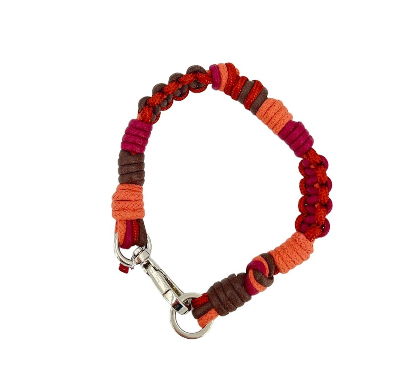 A photo taken from above of a braided macramé cord collar in shades of burgundy, black and light brown with a silver clasp.