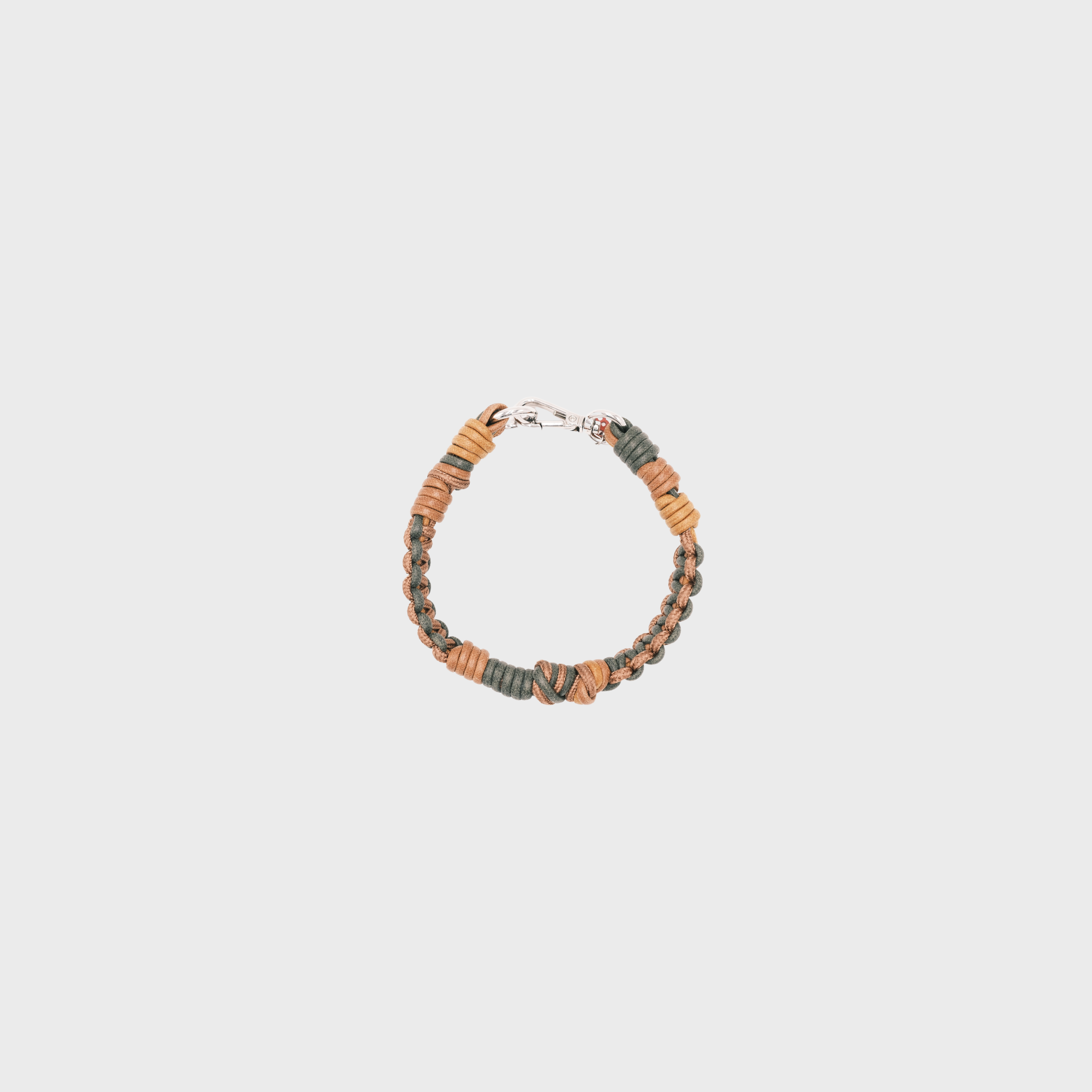 A photo taken from above of a braided macramé cord collar in shades of dark green and brown with a silver clasp.