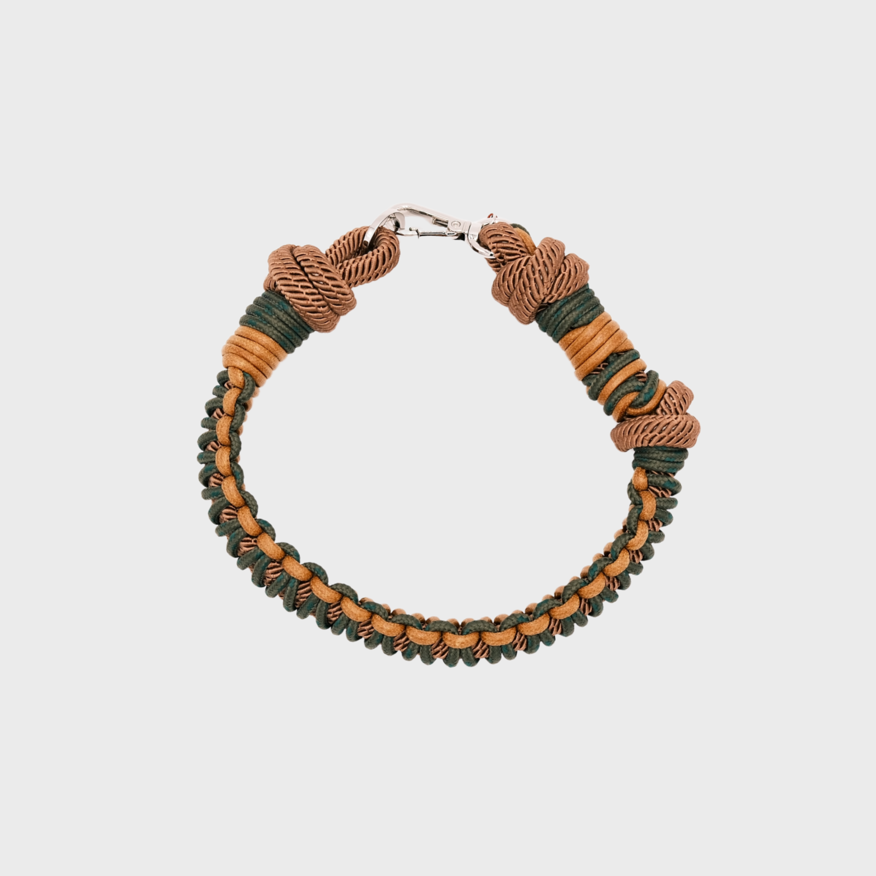 A photo taken from above of a braided macramé cord collar in shades of dark green and yellow with a silver clasp.