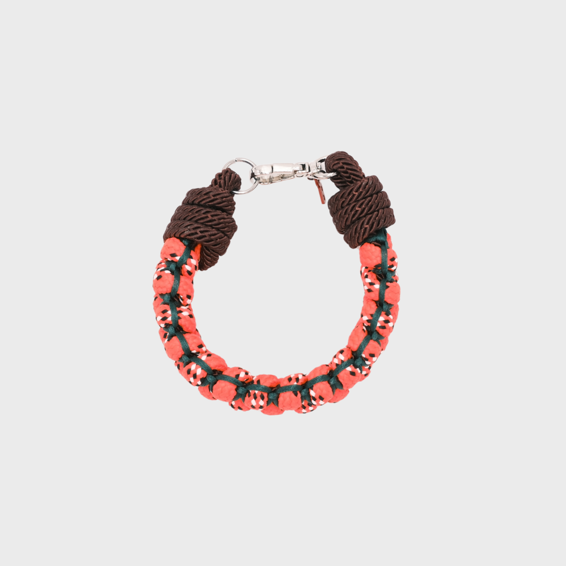 A photo taken from above of a braided macramé bracelet in shades of neon orange, dark green and brown with a silver clasp.