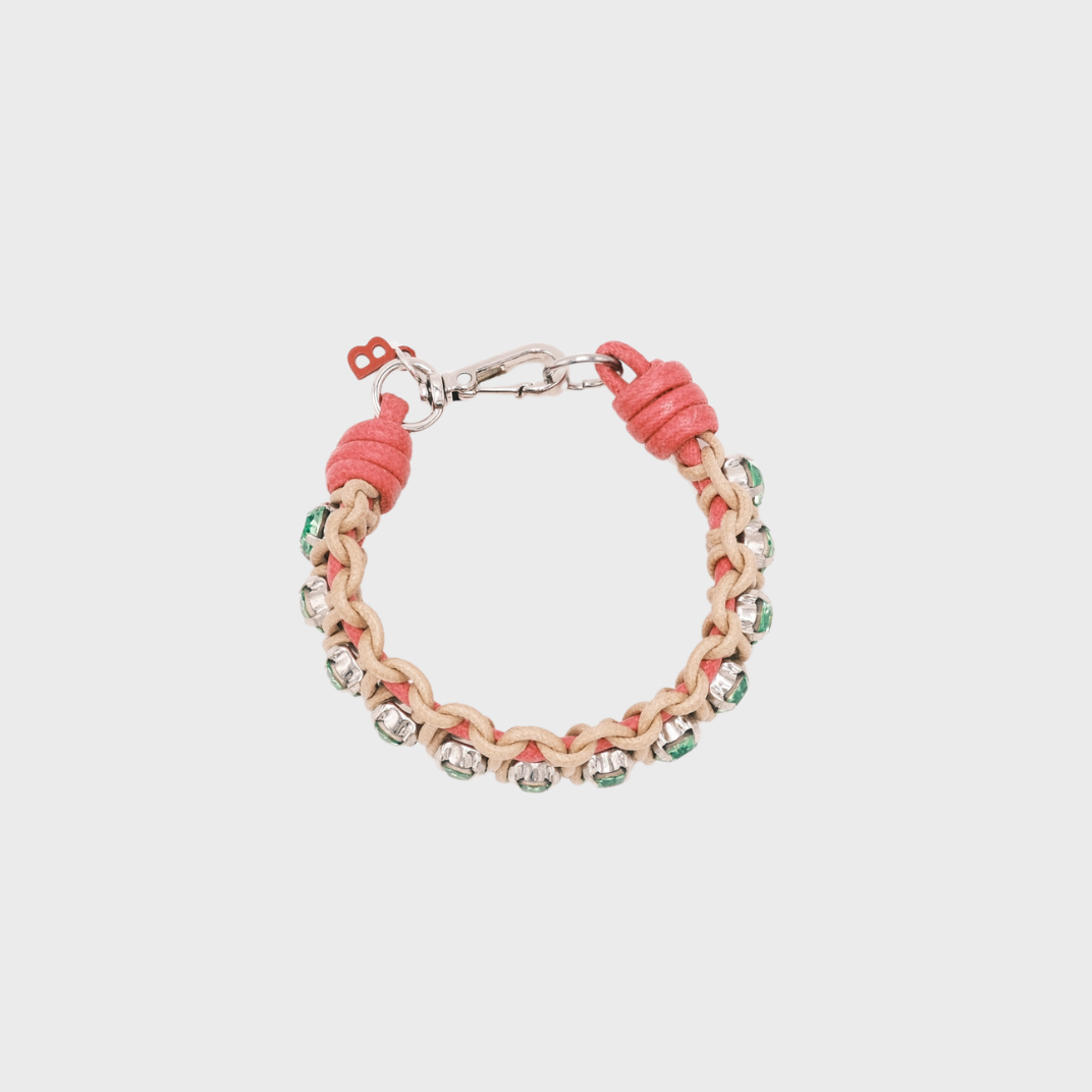 A handmade macramé woven bracelet featuring a mix of pink and beige threads, accented with small green beads and a silver clasp.