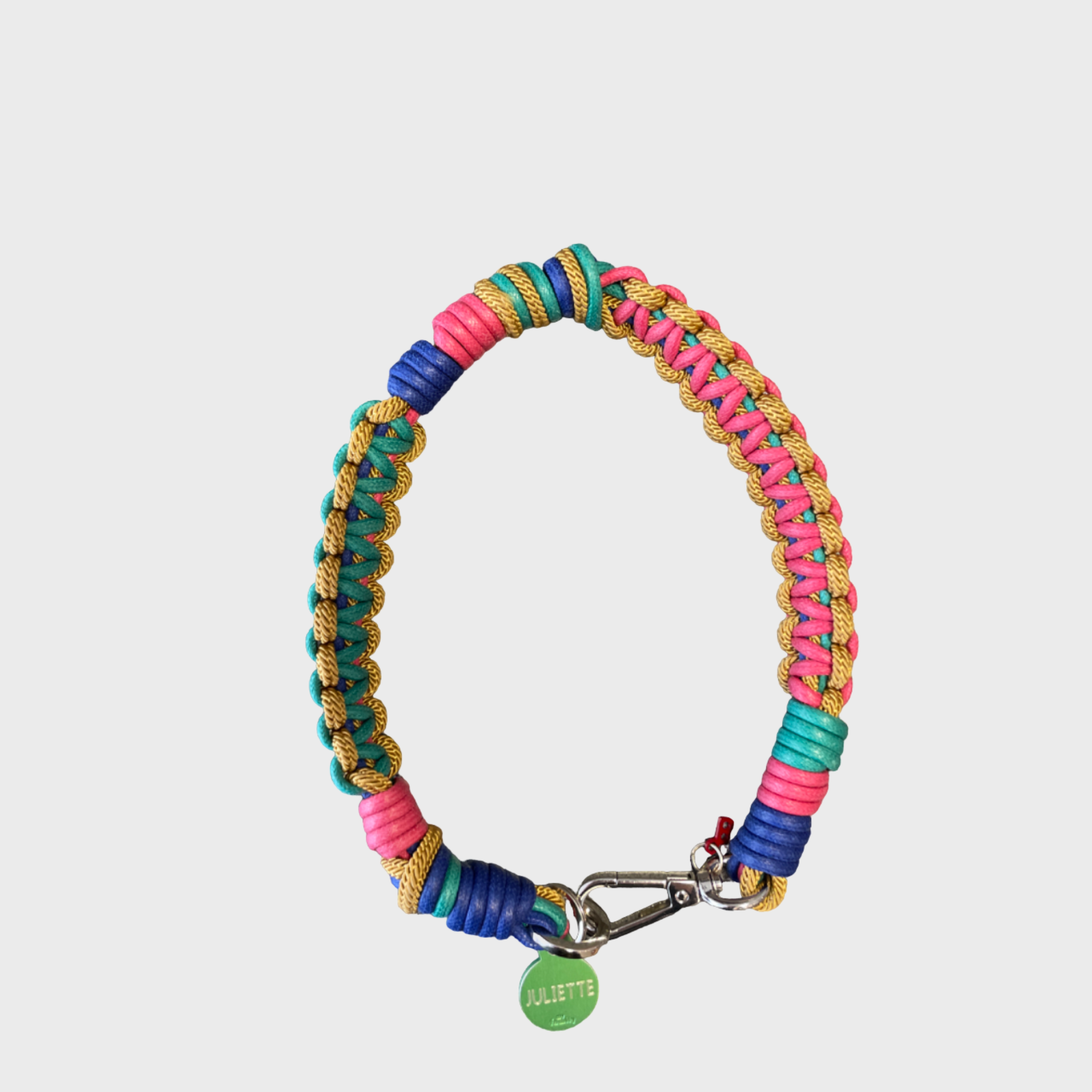 A photo taken from above of a braided macramé cord collar in shades of pink, green, yellow and blue with a silver clasp.