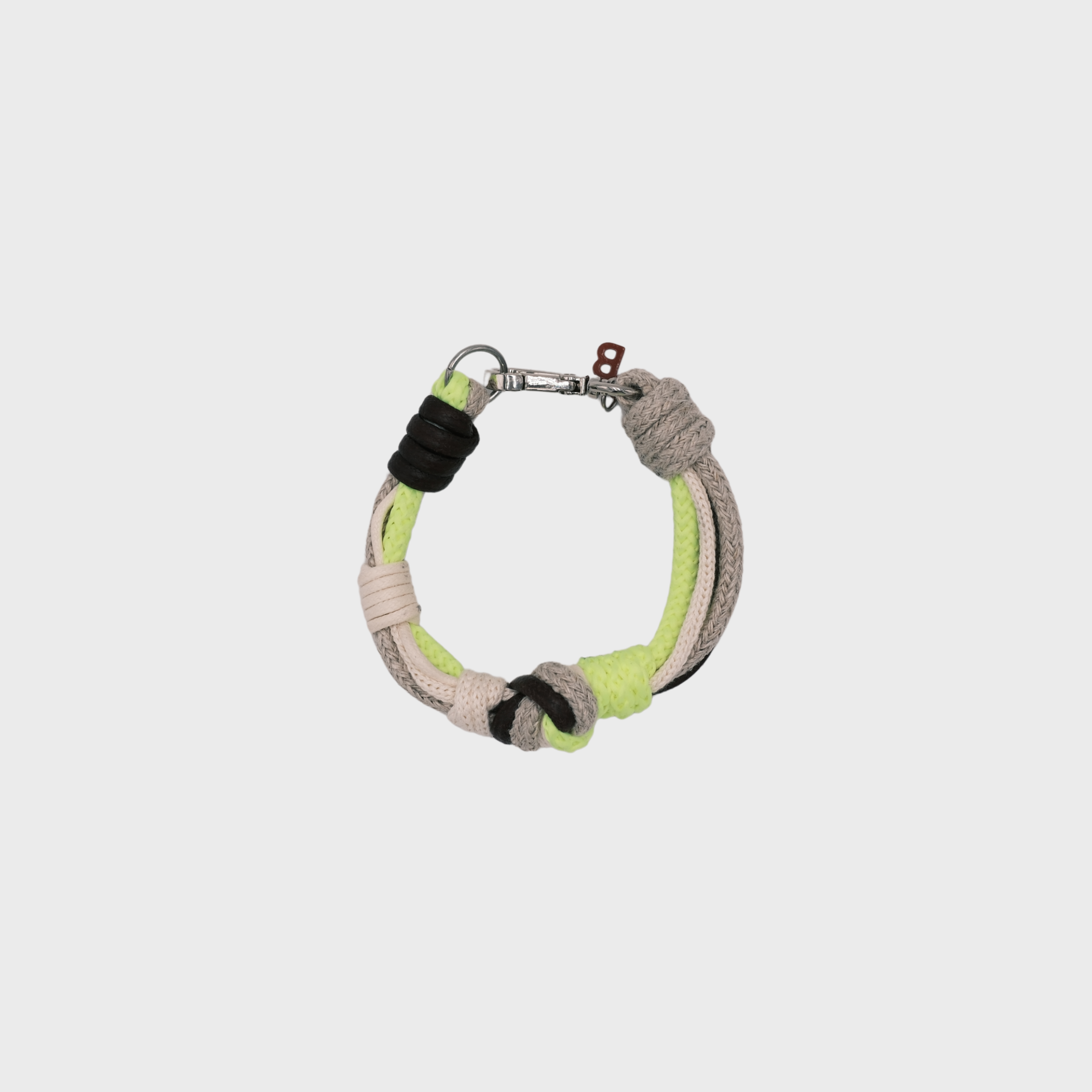 A photo taken from above of a knotted macramé bracelet in shades of neon yellow, beige and brown, with a silver clasp.