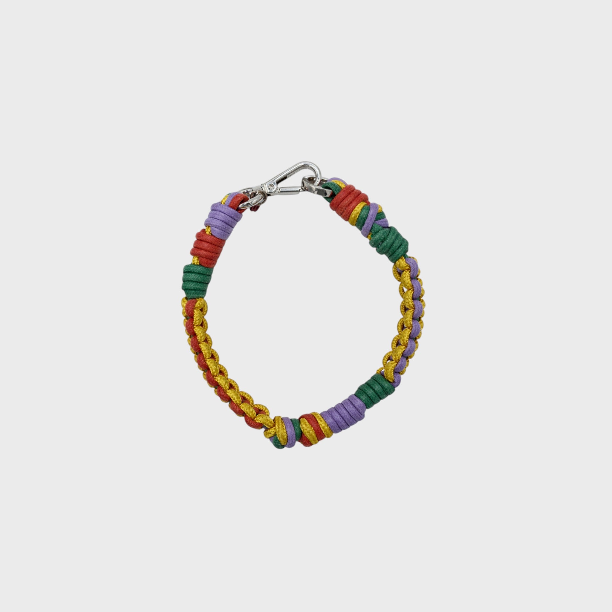 A photo taken from above of a braided macramé cord collar in shades of yellow, purple, red and green with a silver clasp.