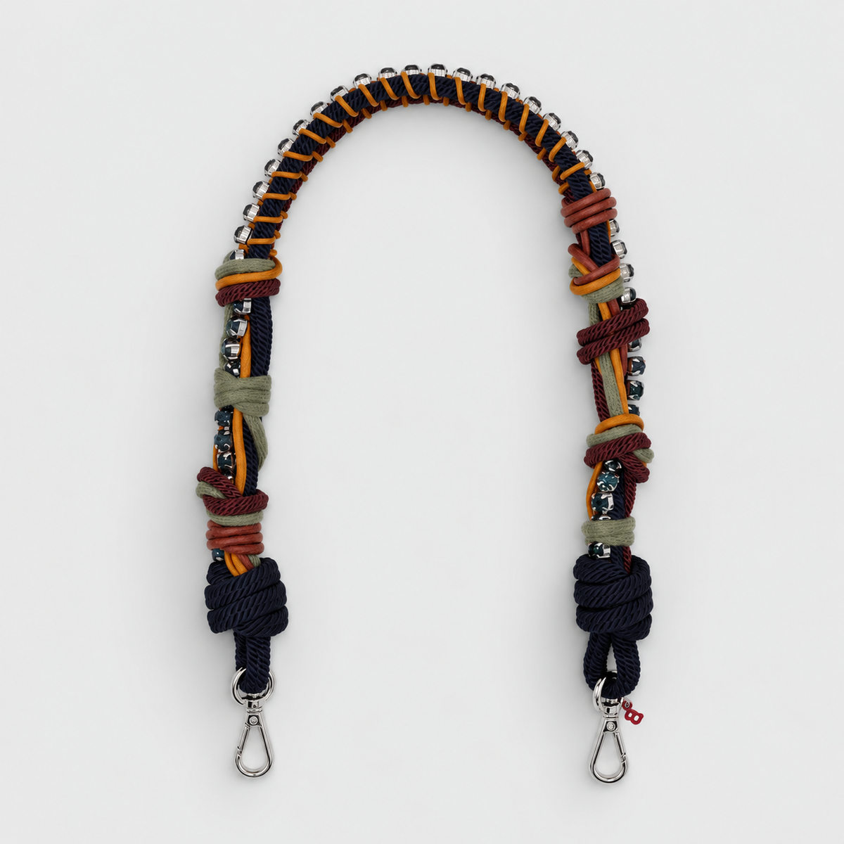 A multi-colored macrame shoulder strap with silver metal snap hooks at the ends, displayed on a light gray background.