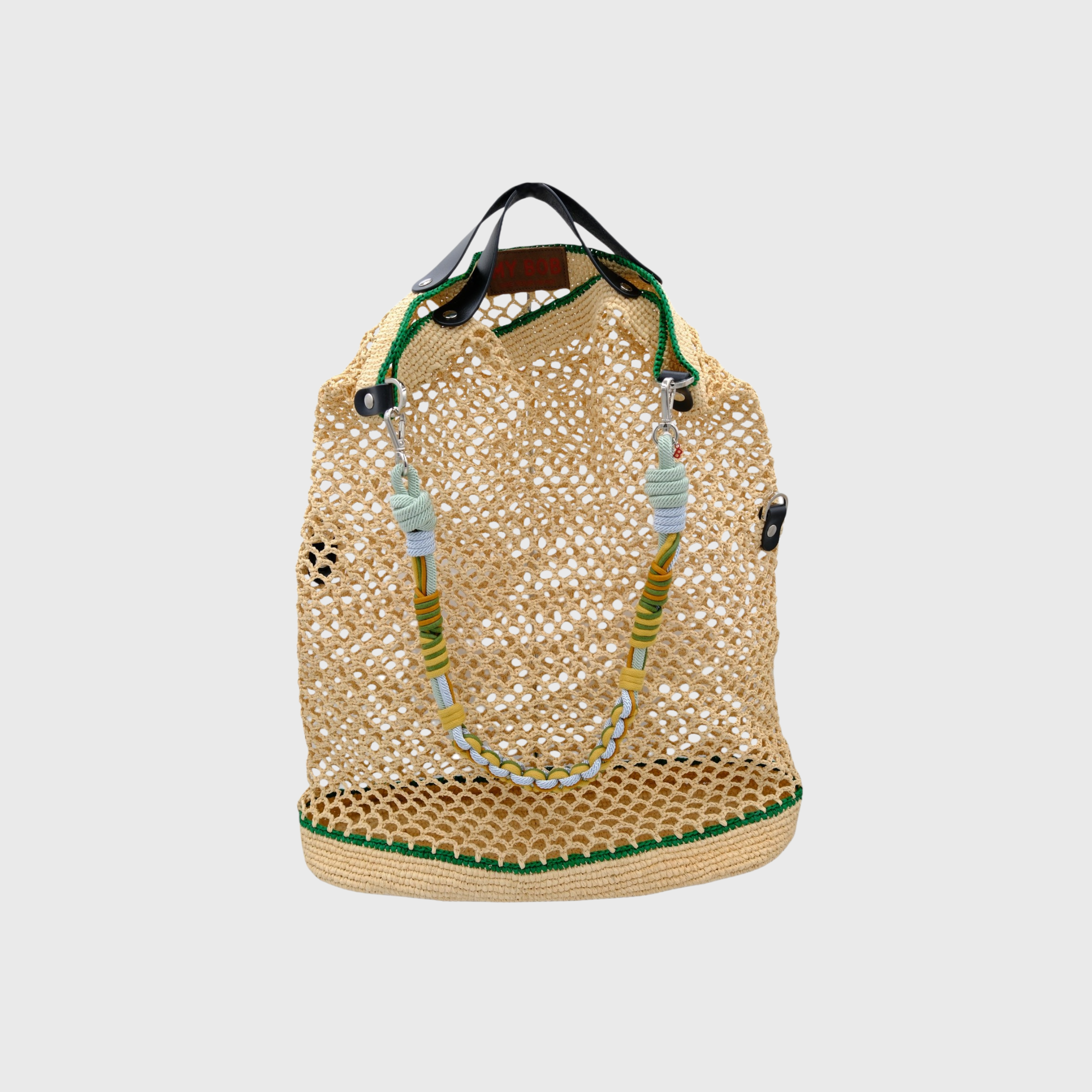 White with green lines raffia bag with a green, light blue and yellow beaded handle on a grey background