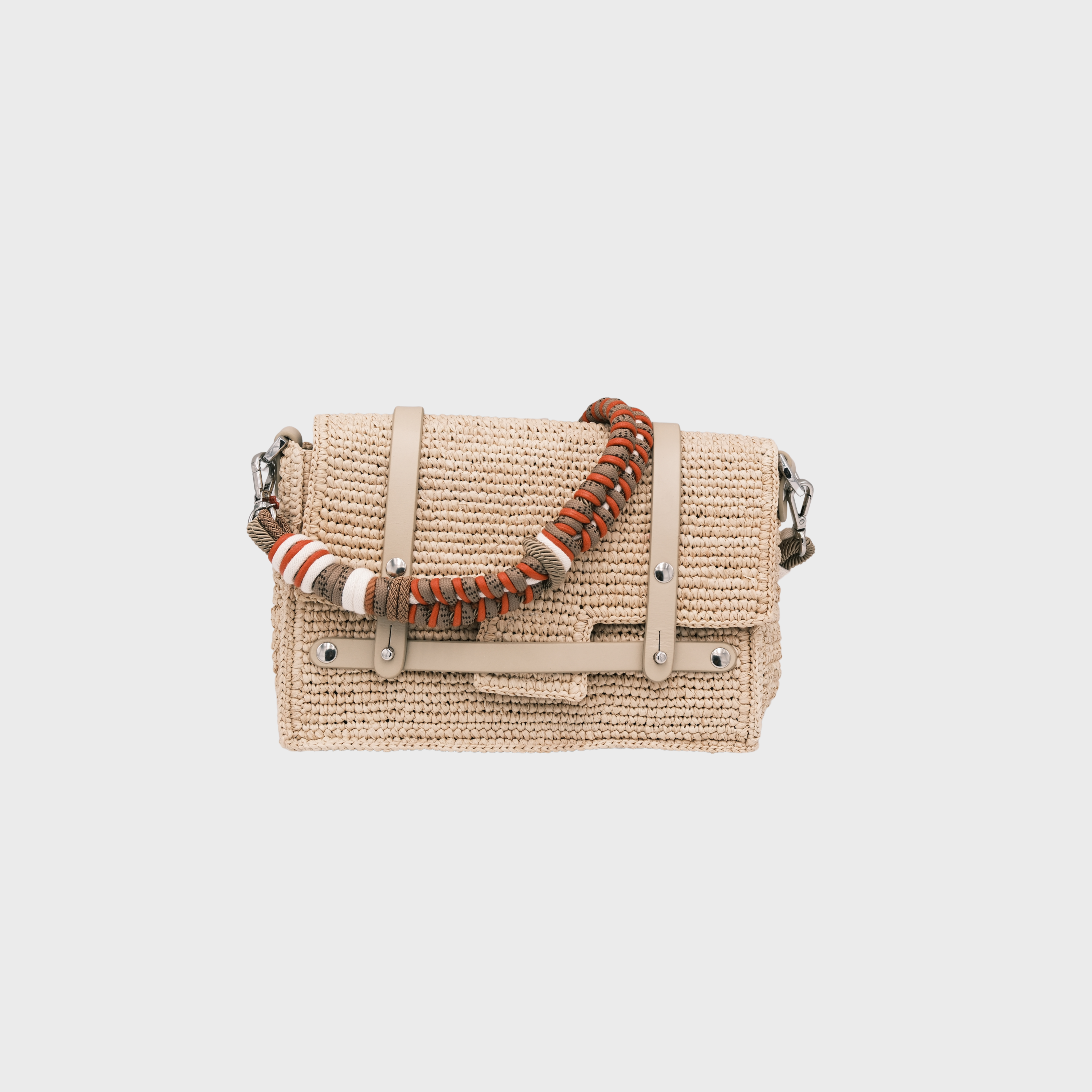 A white raffia shoulder bag with white leather straps and a colorful macramé braided strap featuring red, brown and white. 