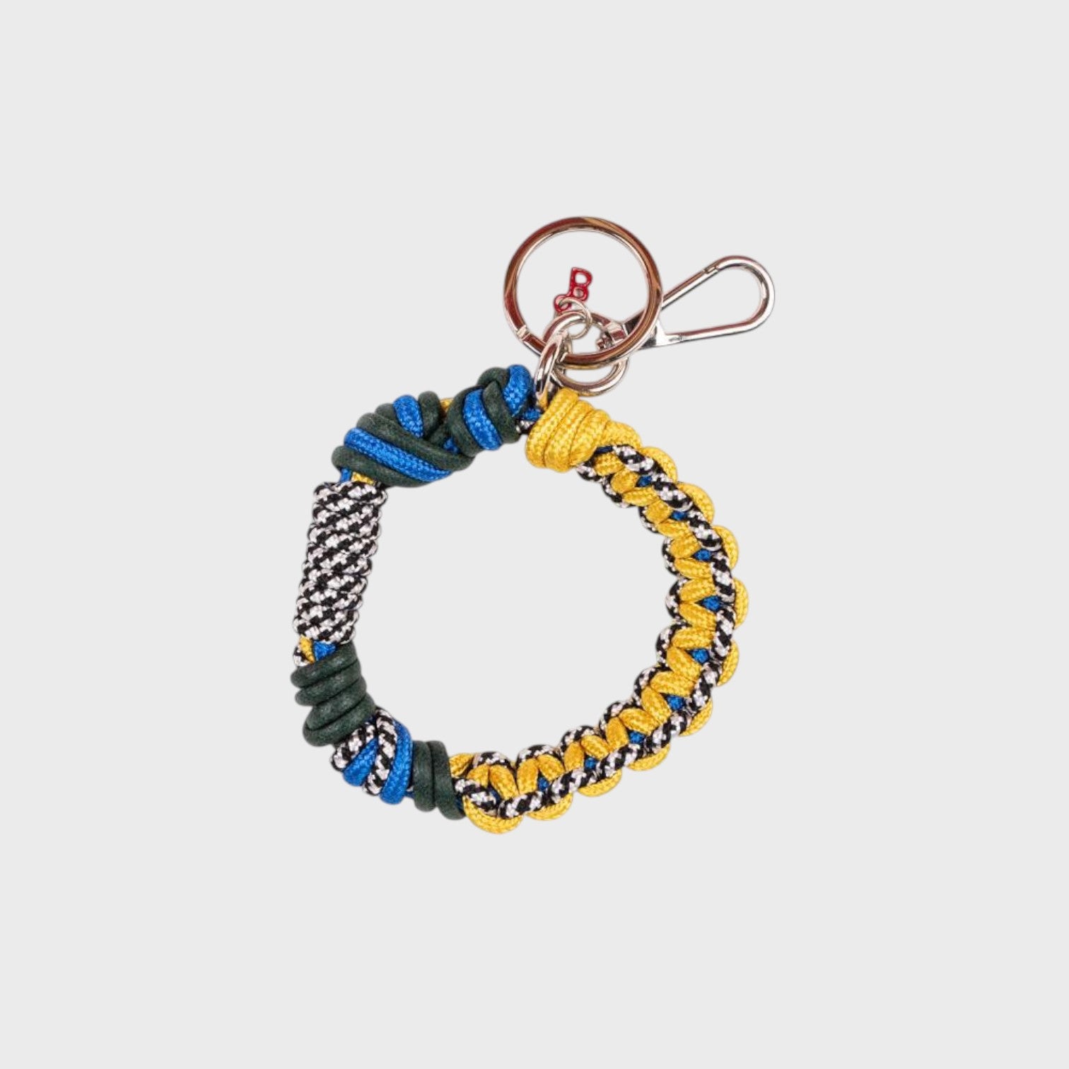A woven macramé key chain with blue, yellow, black and white patterns, inspired by celtic knots, finished with silver-tone metal hardware.