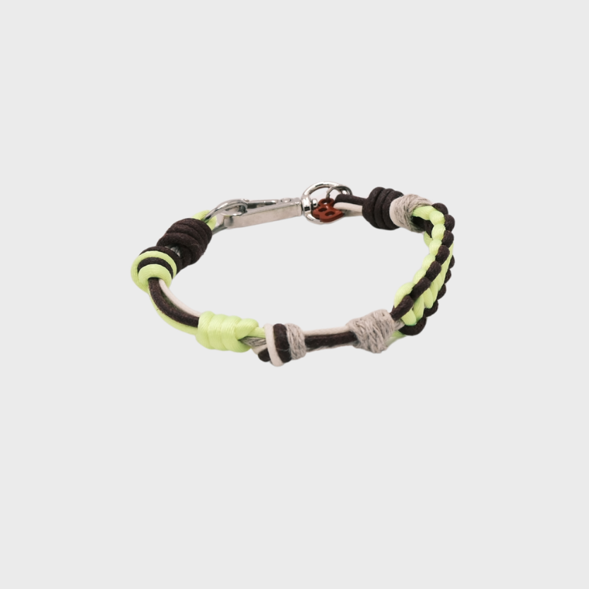 A thin braided bracelet with neon yellow, beige and brown macramé, featuring a silver metal  clasp. 