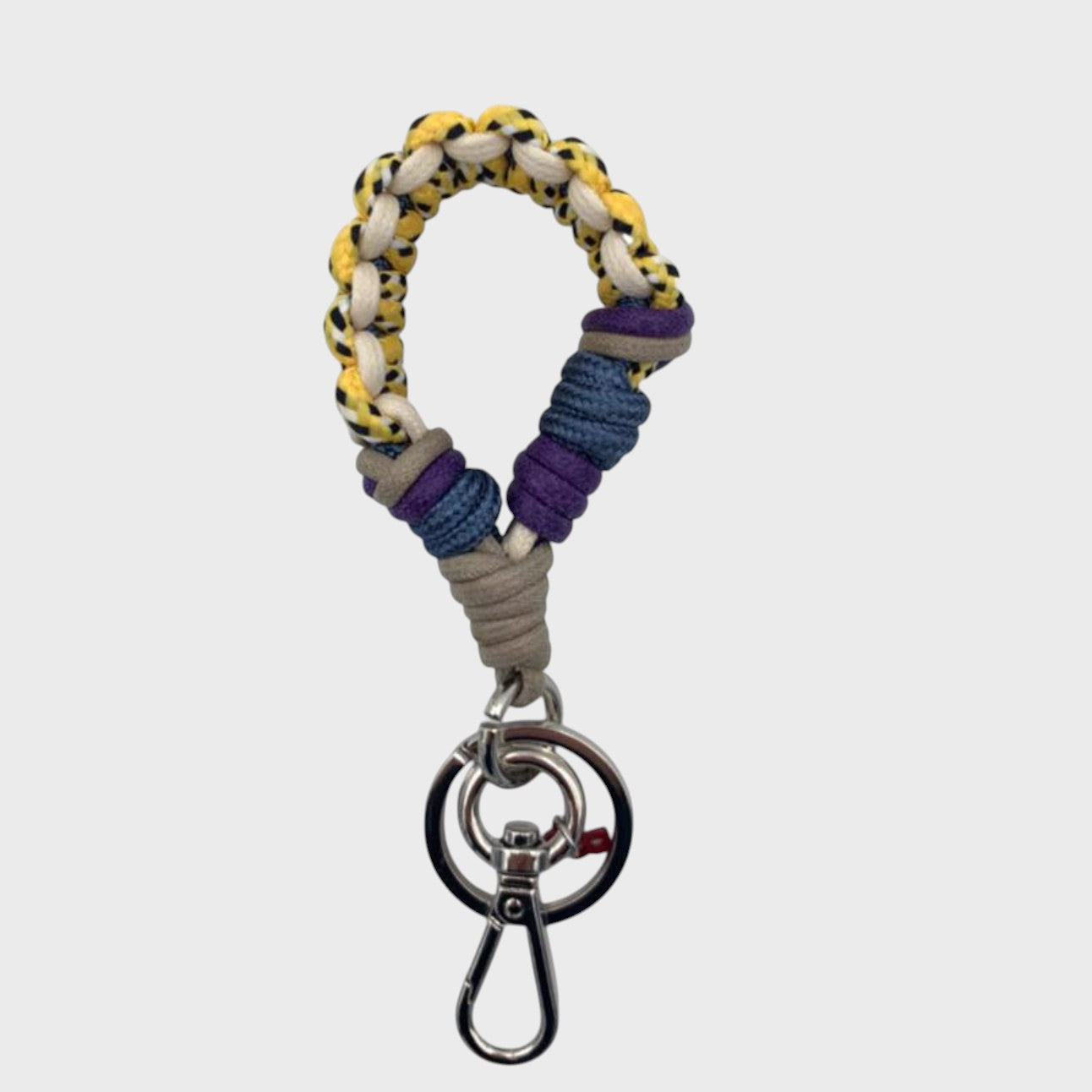 A braided macramé keychain or bag clip in yellow, white, blue, purple and grey, featuring a silver metal clasp. 