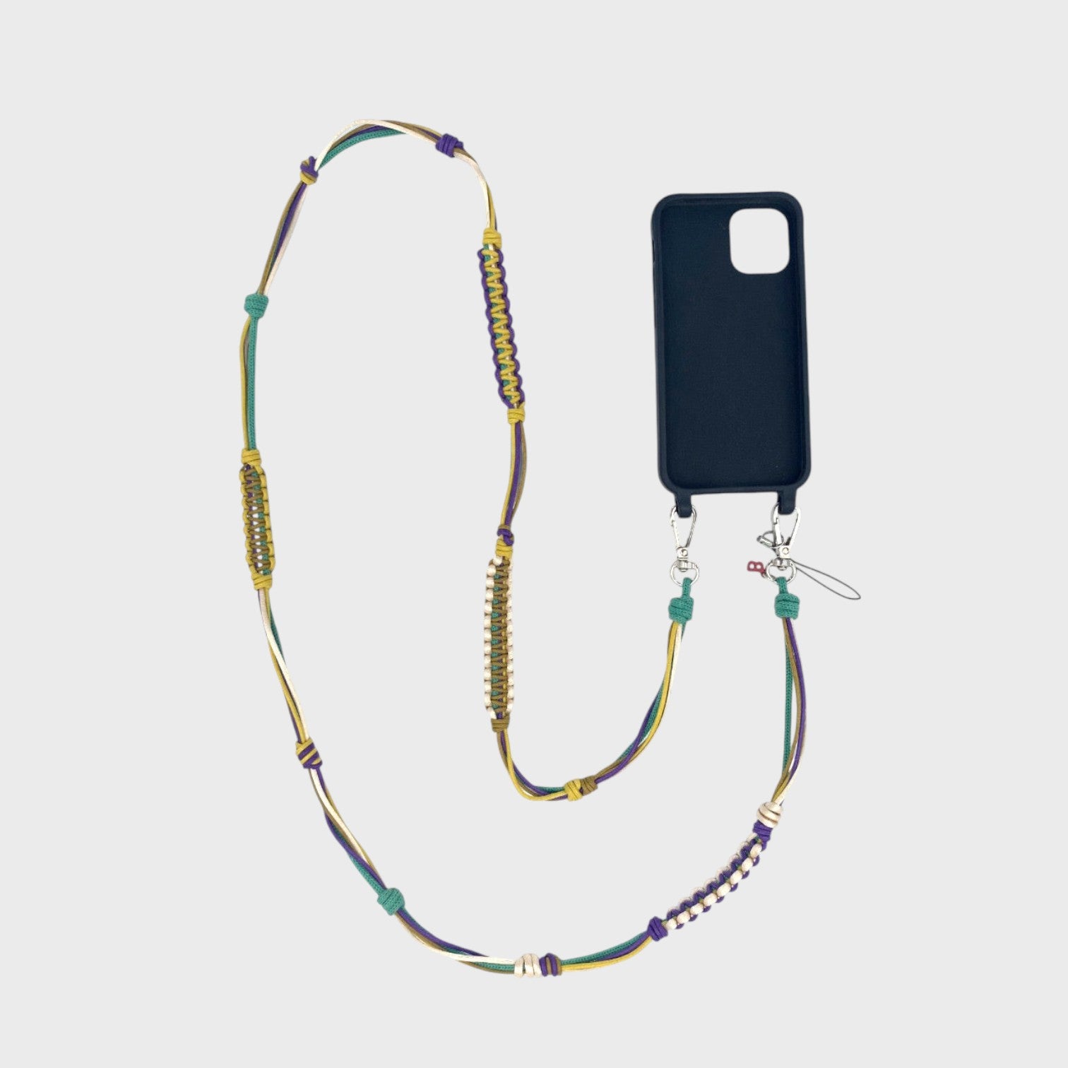 Purple, yellow, green and beige macramé woven phone lanyard with a black phone case on a white background. 