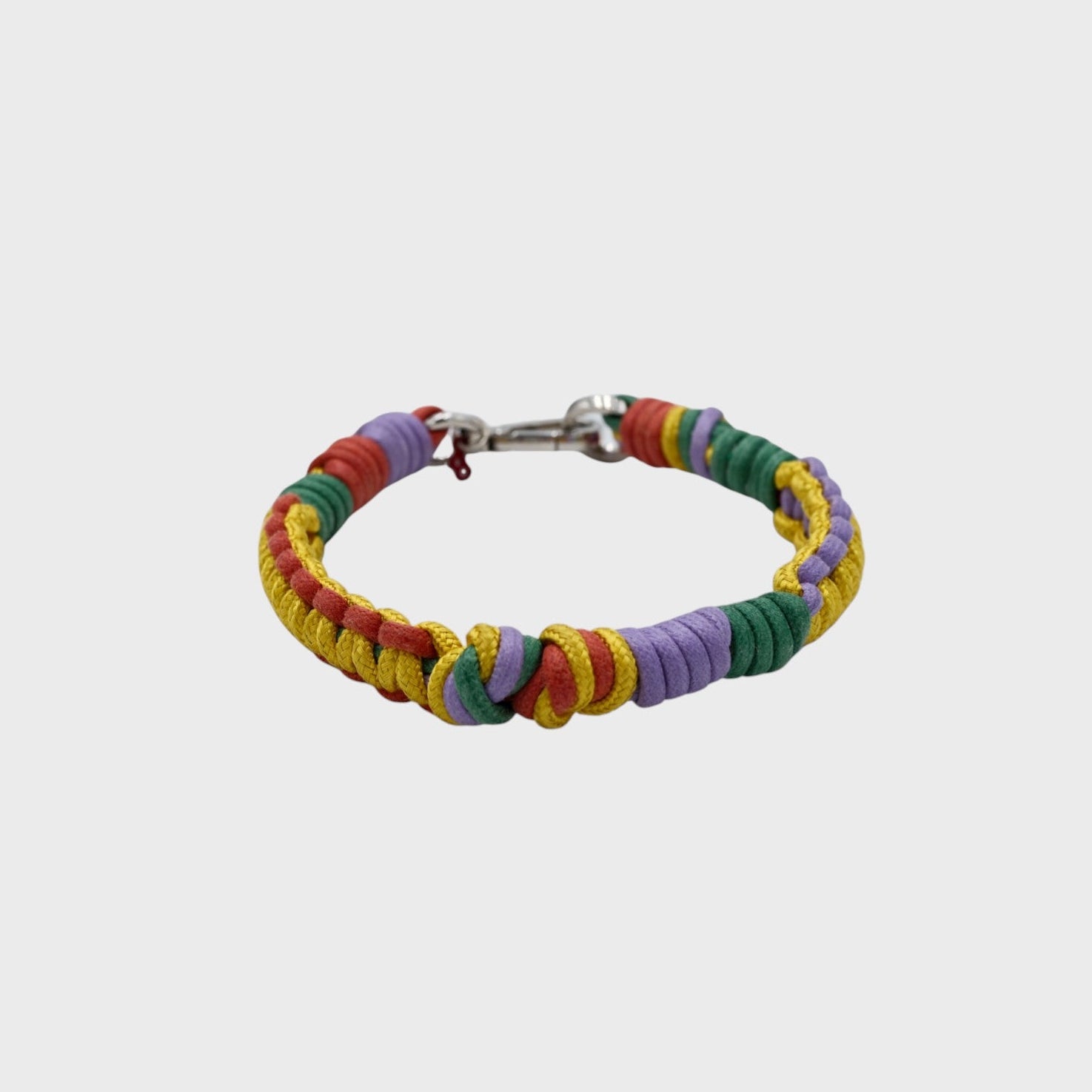 A braided macramé cord collar in shades of yellow, purple, red and green with a silver clasp, centered on a light gray background.