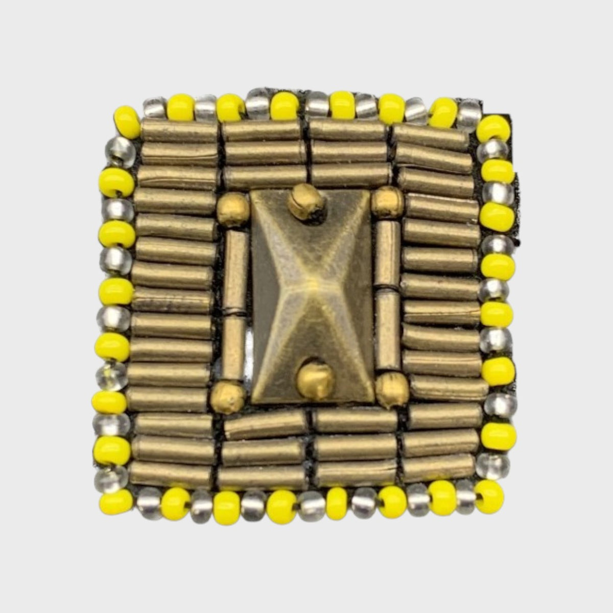 An embroidered brooch representing a button with yellow and golden details and pearls. 