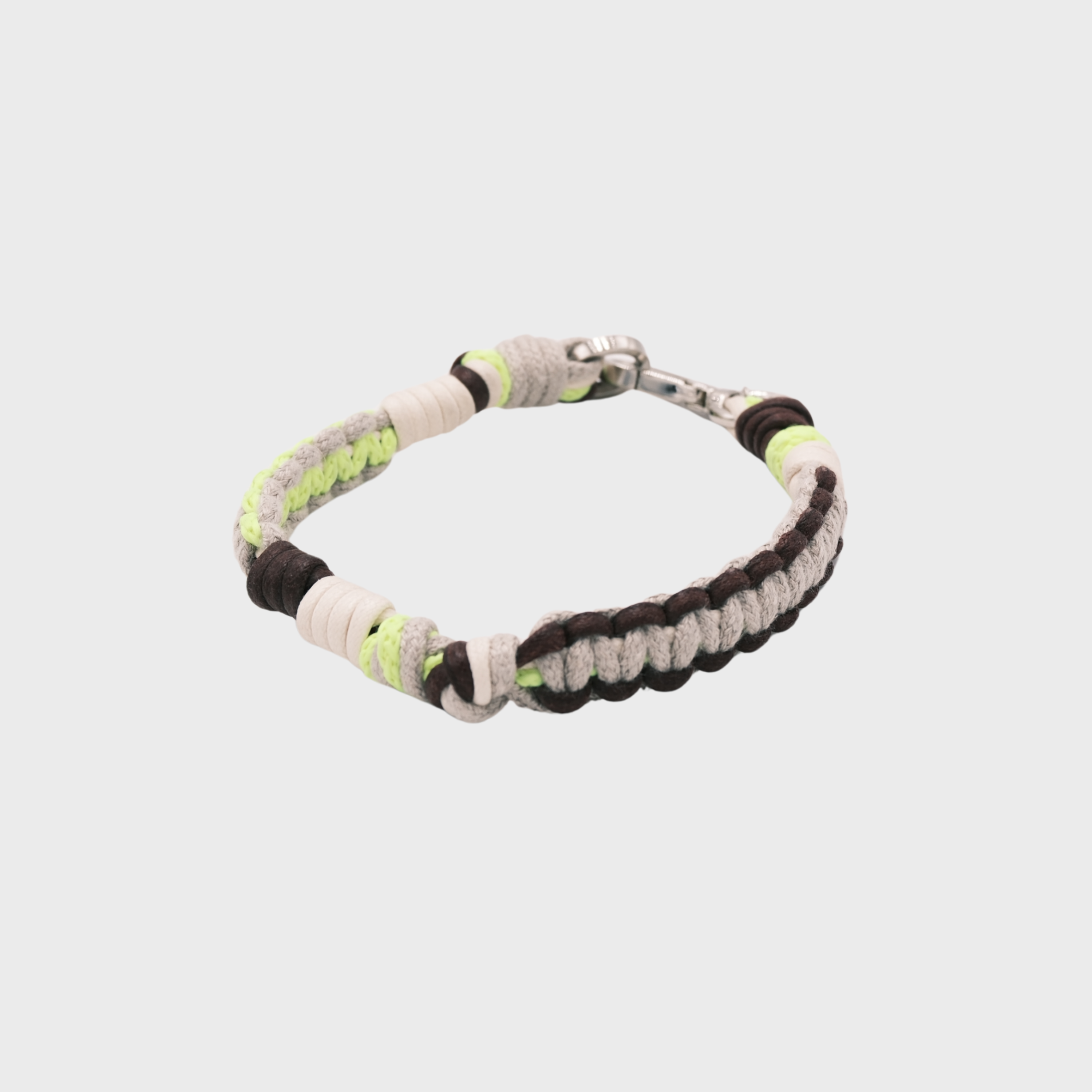 A braided macramé cord collar in shades of neon yellow, beige and brown with a silver clasp, centered on a light gray background.