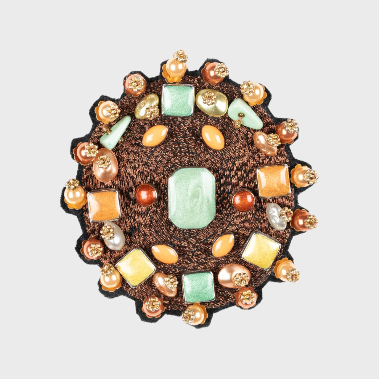 An embroidered brooch representing a brown yourte, with several stone on it. 