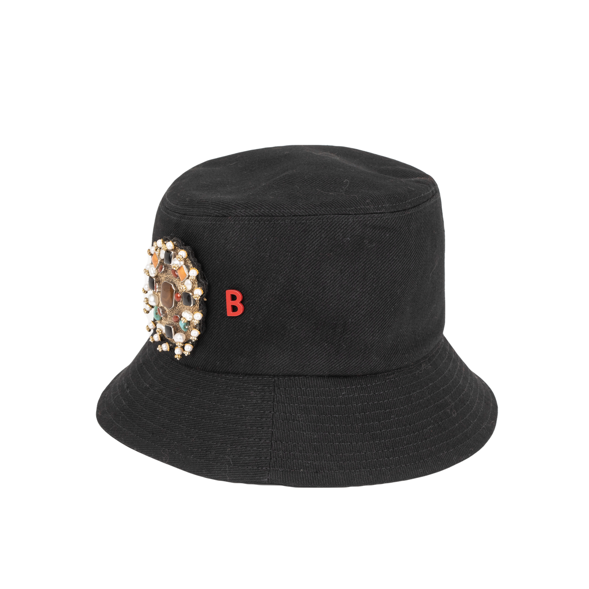 A black cotton bucket hat with an embroidered brooch representing the inside of a yourte pinned on it. 