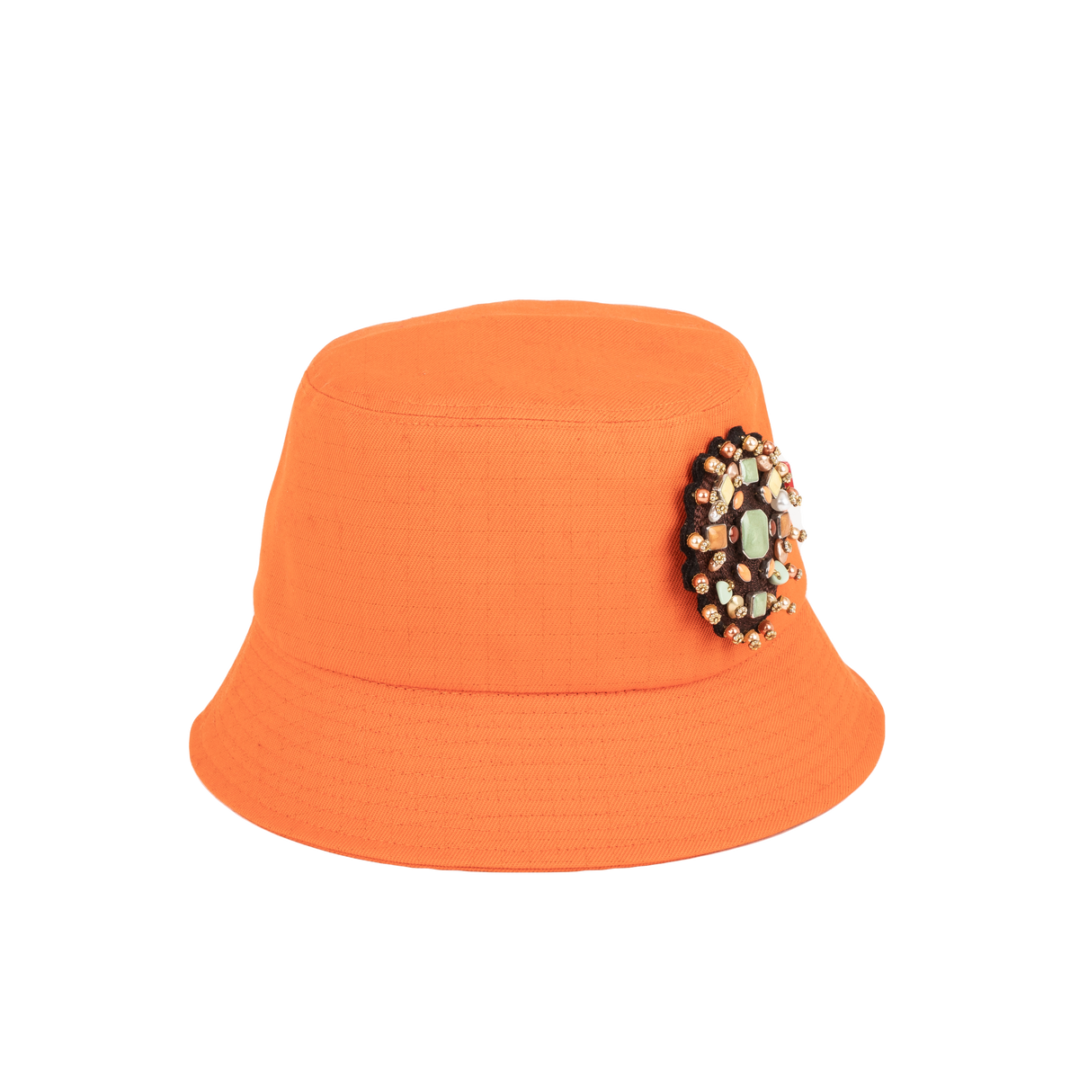 An orange cotton bucket hat with a yourte brooch pinned on it. 