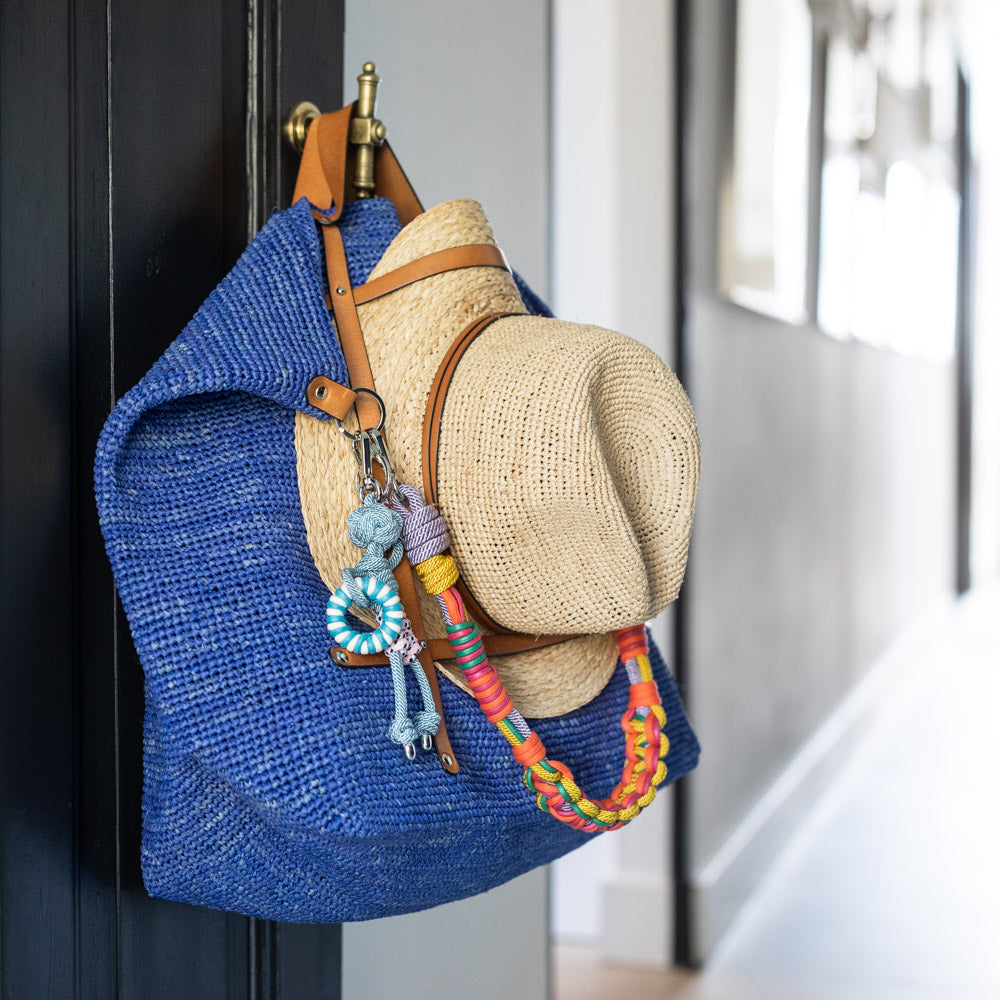 Multicolored braided macramé bag strap in yellow, lilac, orange, and green shown on a blue raffia CANDIDE Weekender bag.