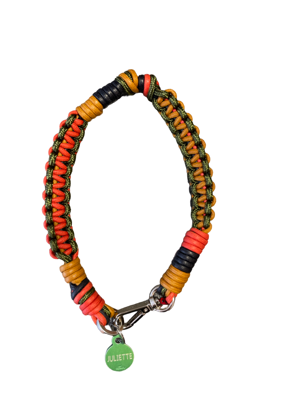 A photo taken from above of a braided macramé cord collar in shades of light brown, red and green with a silver clasp.